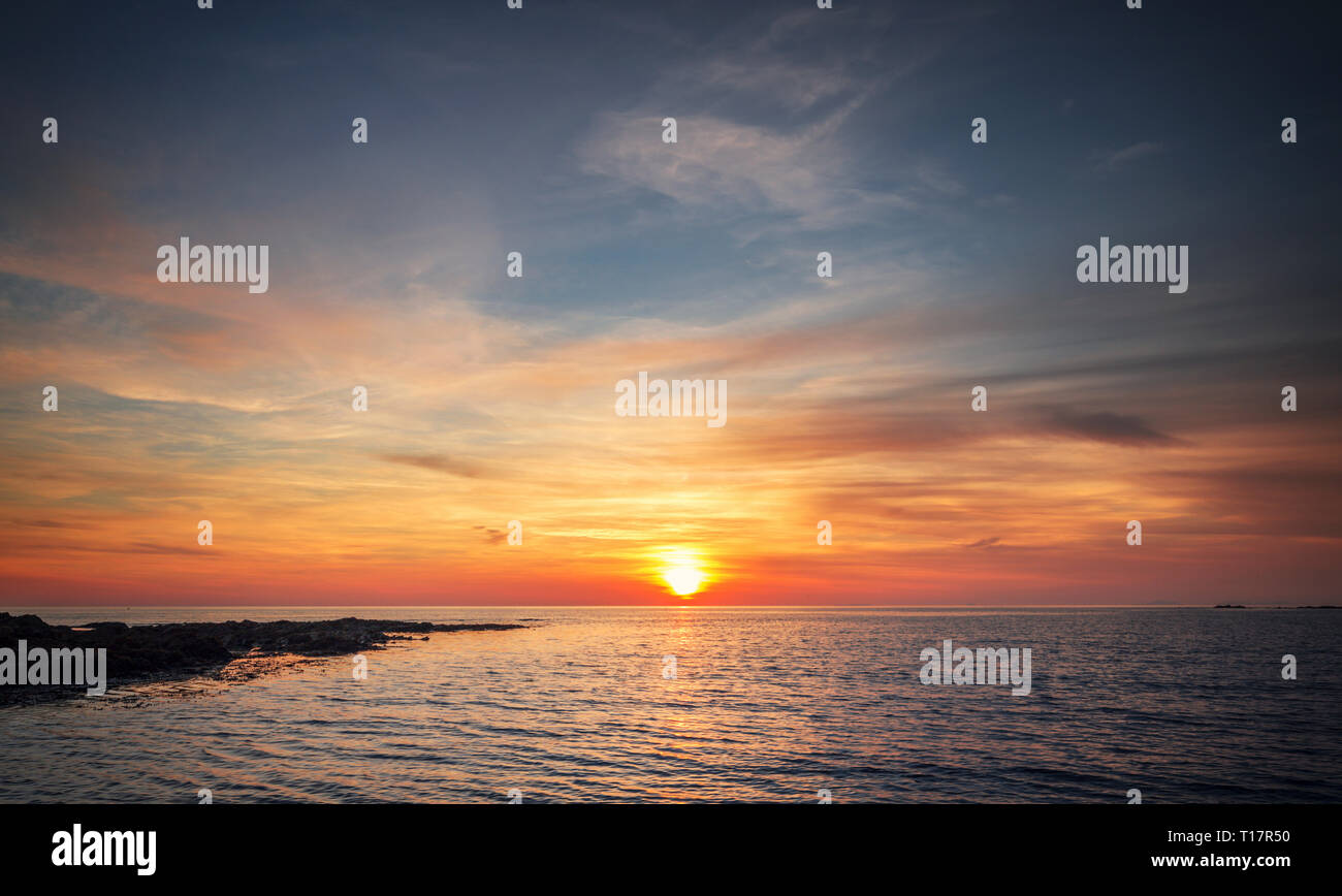 Coucher de soleil coloré chaud ciel au-dessus de la mer calme à marée basse dans le Nord du Pays de Galles, Aberystwyth Banque D'Images