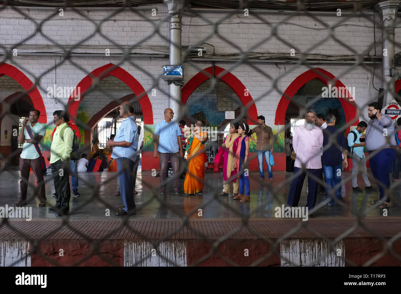 Vue à travers la prise constante sur le fil en face d'un train de voyageurs's bogey fenêtre dans Mumbai, Inde, vers la plate-forme à la gare et les passagers Byculla Banque D'Images