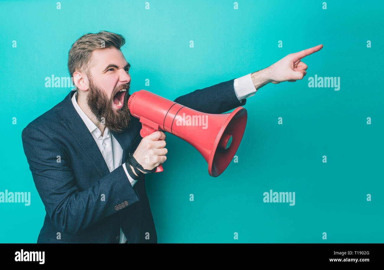 Guy grave est à la ligne droite. Il est orienté et commandant. L'homme n'est crier dans le haut-parleur. Isolé sur fond bleu Banque D'Images
