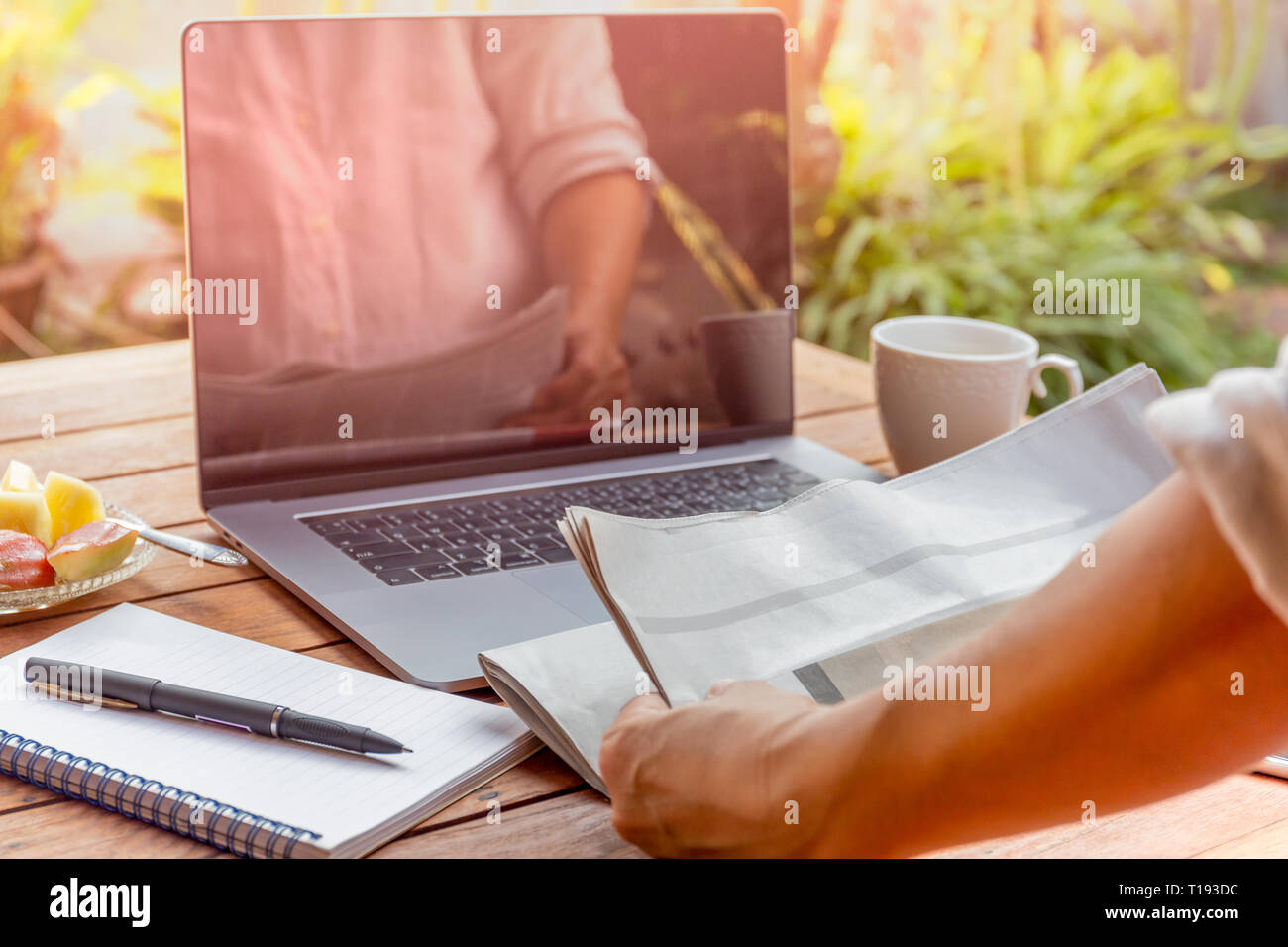 Businessman reading newspaper avec stylet et ordinateur portable et ordinateur portable sur la table. Banque D'Images