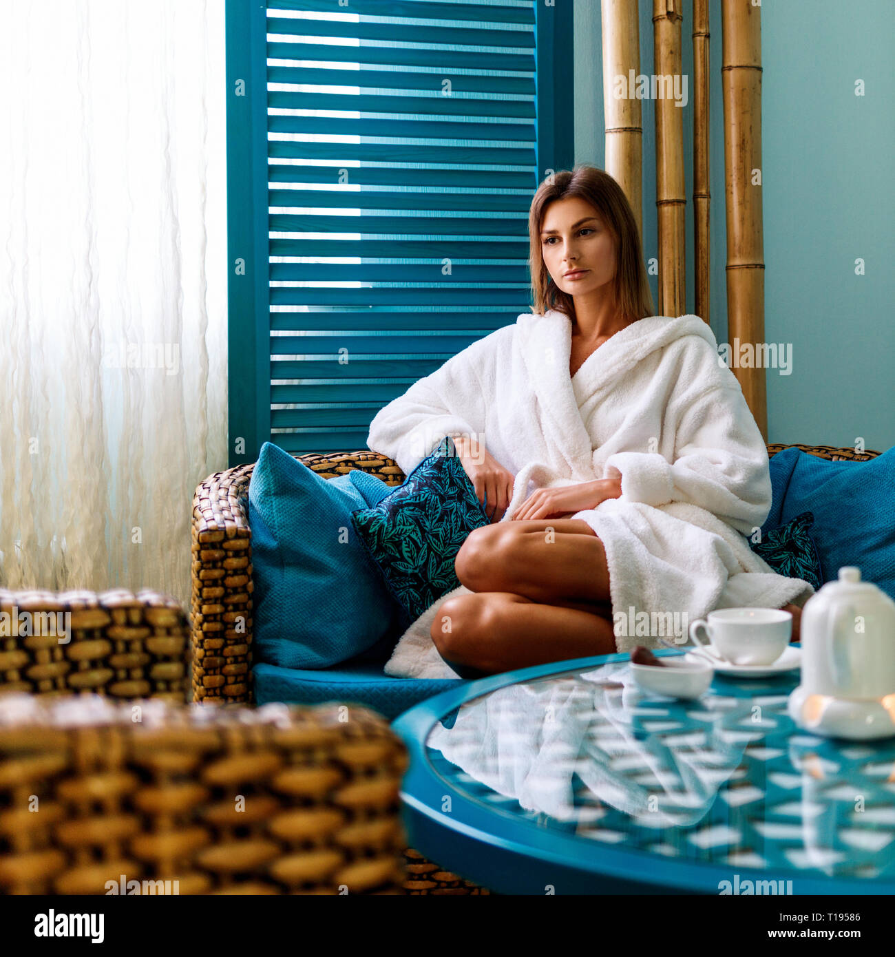 Woman in bathrobe drinking tea in spa salon. Banque D'Images