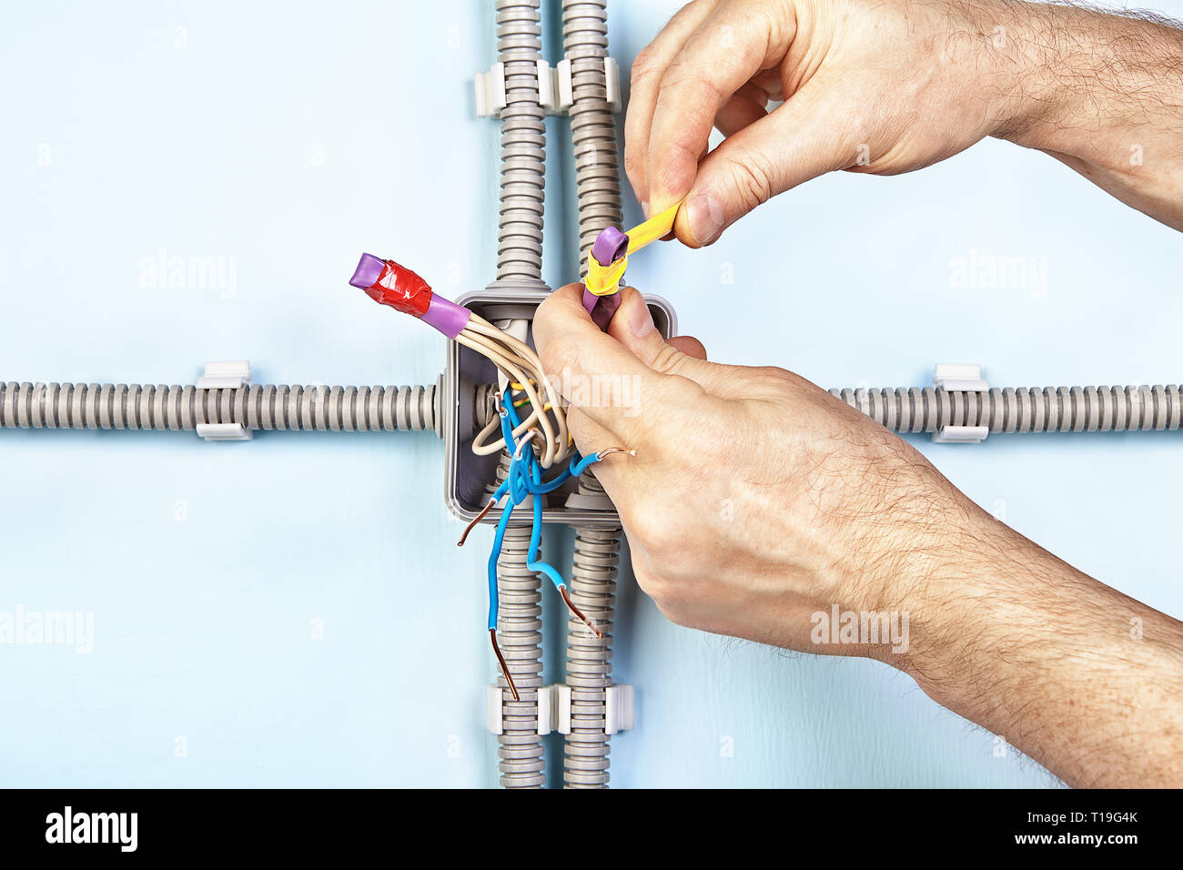 L'enregistrement est électricien les extrémités des fils dans le tube thermorétractable au cours de l'installation de la boîte de jonction. Banque D'Images