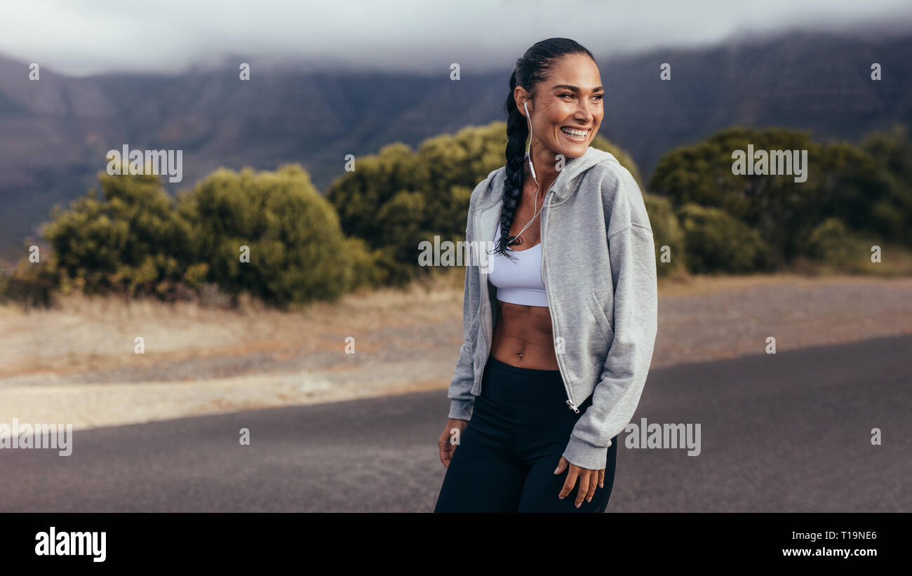 Sweat femme sportive en plein air permanent dans la matinée à l'écart et souriant. Femme fitness gaies sur exercices du matin. Banque D'Images