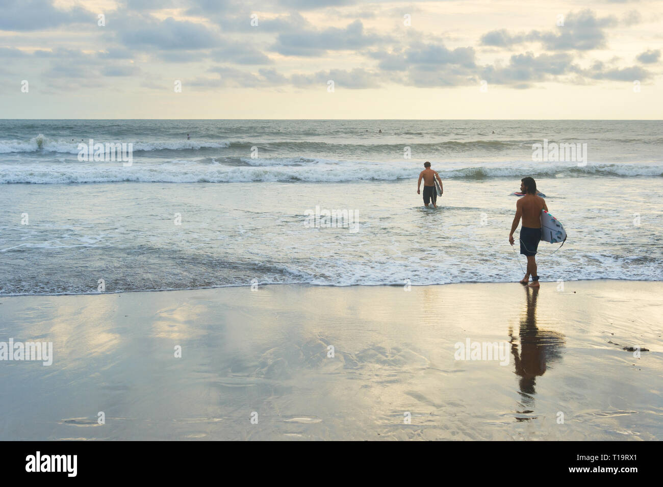 L'ÎLE DE BALI, INDONÉSIE - 12 février 2017 : les hommes avec des planches au coucher du soleil plage Océan surf session pour aller Banque D'Images