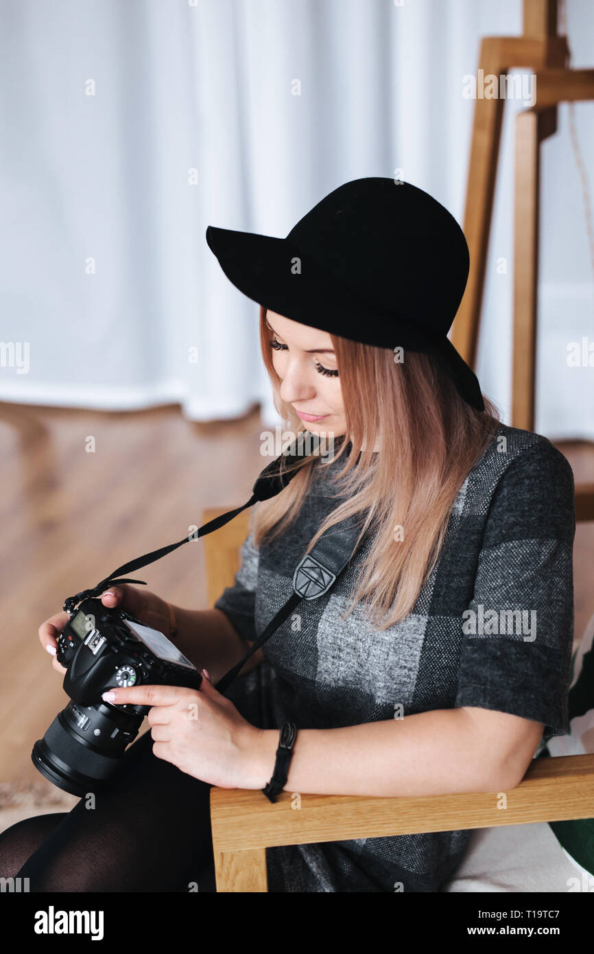 Jeune femme photographe élégant contrôle des photos sur un appareil photo en studio Banque D'Images