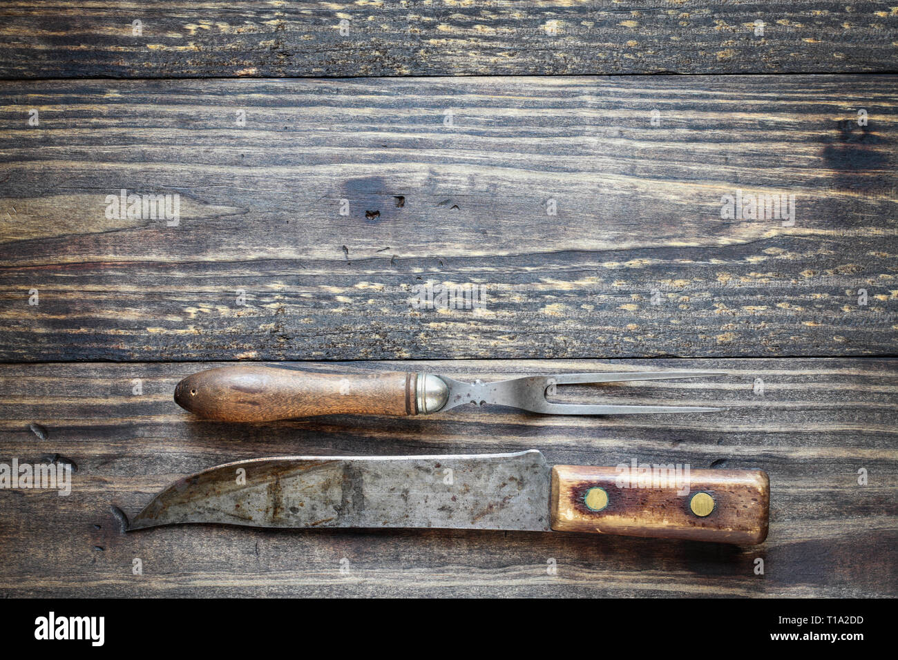 Fourchette à viande antique et Butcher's knife par-dessus une table rustique en bois / arrière-plan. Droit tourné à partir de la vue de dessus. Banque D'Images