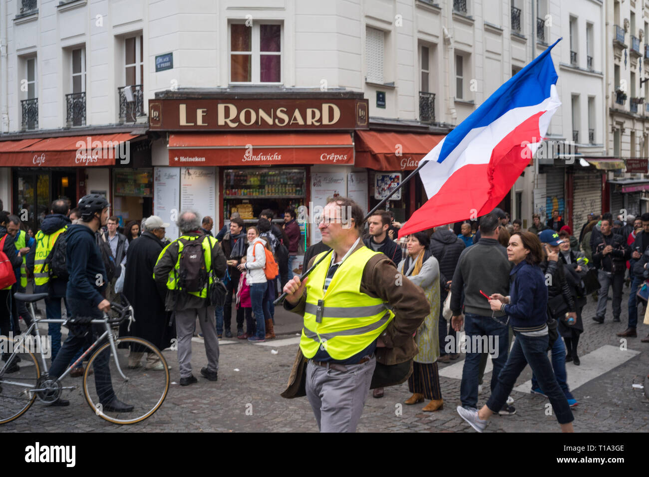 Un manifestant tient un drapeau français à Montmartre, un quartier du nord dans la capitale française. Au cours de la XIX Loi du gilet jaune, mouvement français manifestants se rassemblent à l'instar de basilic Sacré-Cœur, au nord de Paris. Banque D'Images