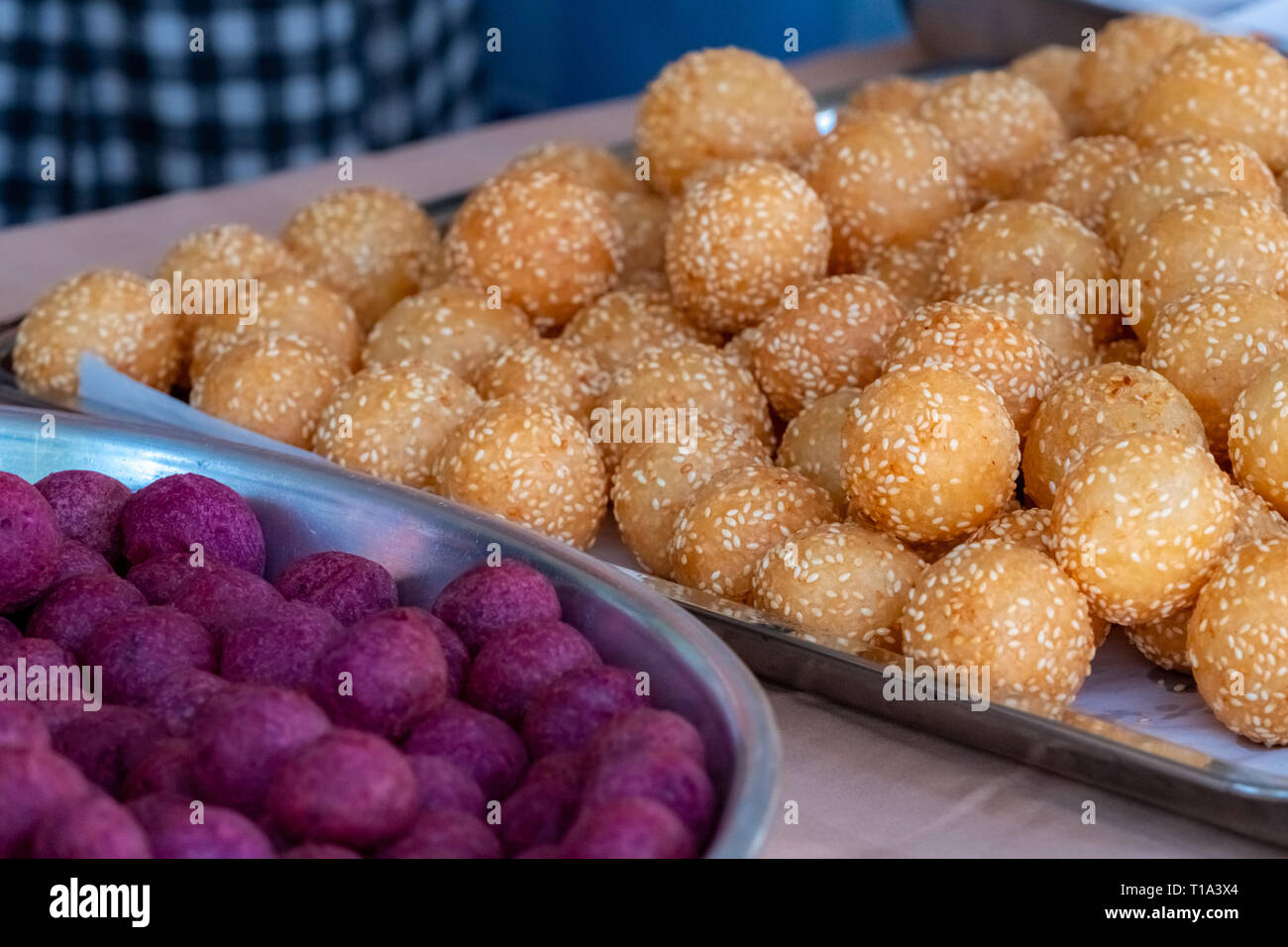 Dessert traditionnel thaï. Boules de sésame frits et frits sweet potato balls sur bac acier inoxydable de vendeur. Brun pourpre et des bonbons boules. Banque D'Images