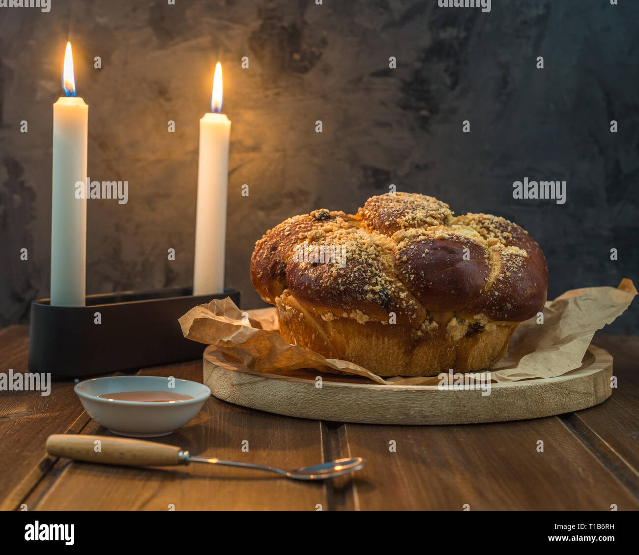 Pain Challah douce sur une plaque ronde boisées sur table en bois brun avec du miel et deux bougies le soir de Shabbat décisions Kidush / fond noir avec Banque D'Images