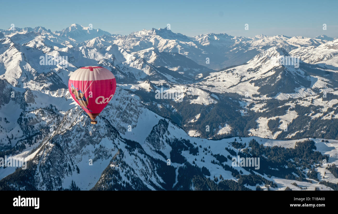 Un ballon à air chaud prend un vol sur les hautes crêtes couvertes de neige des Alpes de Suisse centrale. Banque D'Images