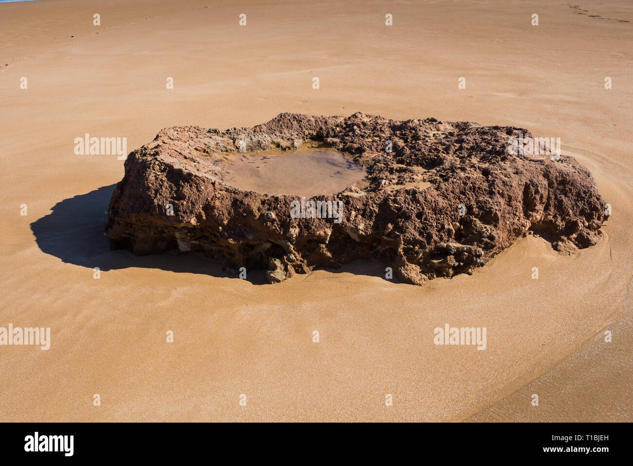 Plage de sable de l'océan Atlantique avec un rocher dans une forme d'un lavoratory, avec une flaque d'eau de mer à l'intérieur. Plage Beddouza, Maroc. Banque D'Images