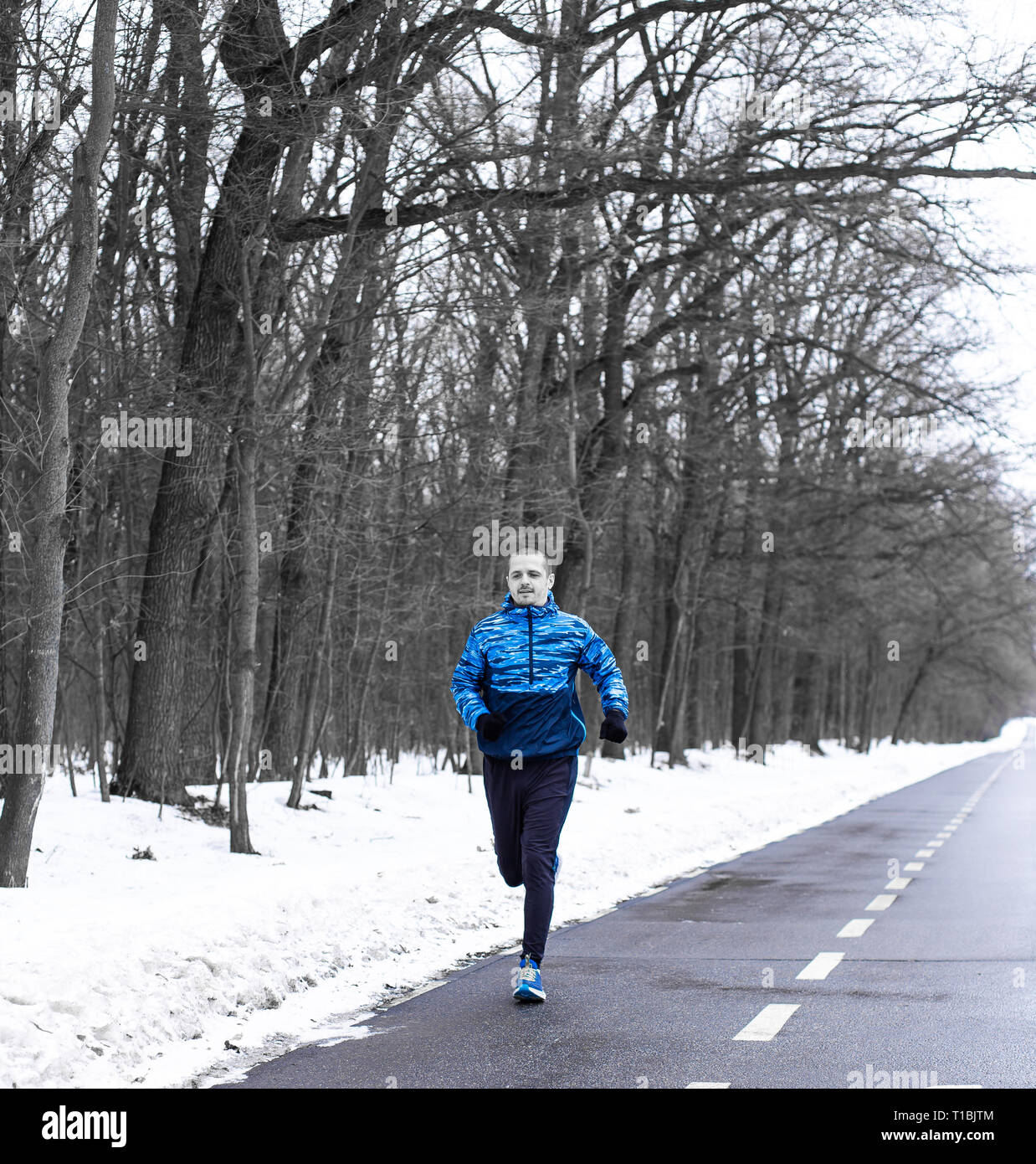 Homme qui court sur la voie près de la forêt d'hiver le matin Banque D'Images