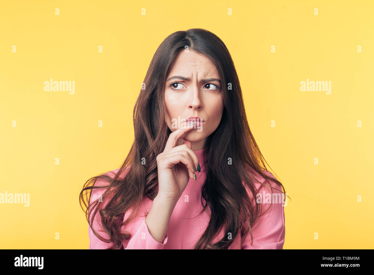 Thoughtful confondu woman isolated over fond jaune. Doute concept Banque D'Images