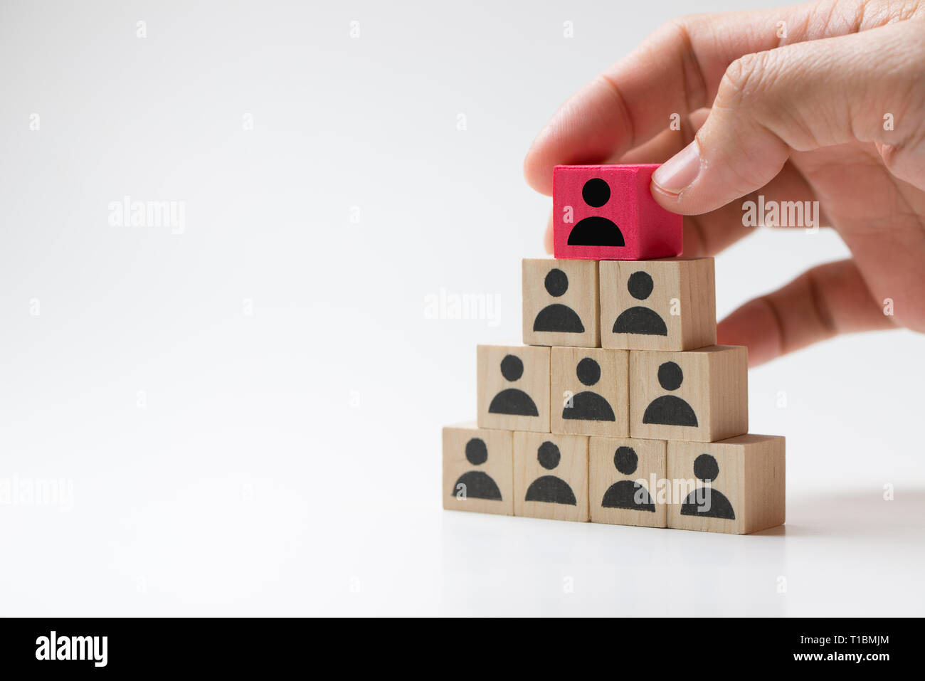 Mettre la main sur le dessus du bloc cube en bois pyramide pour concept de leadership Banque D'Images