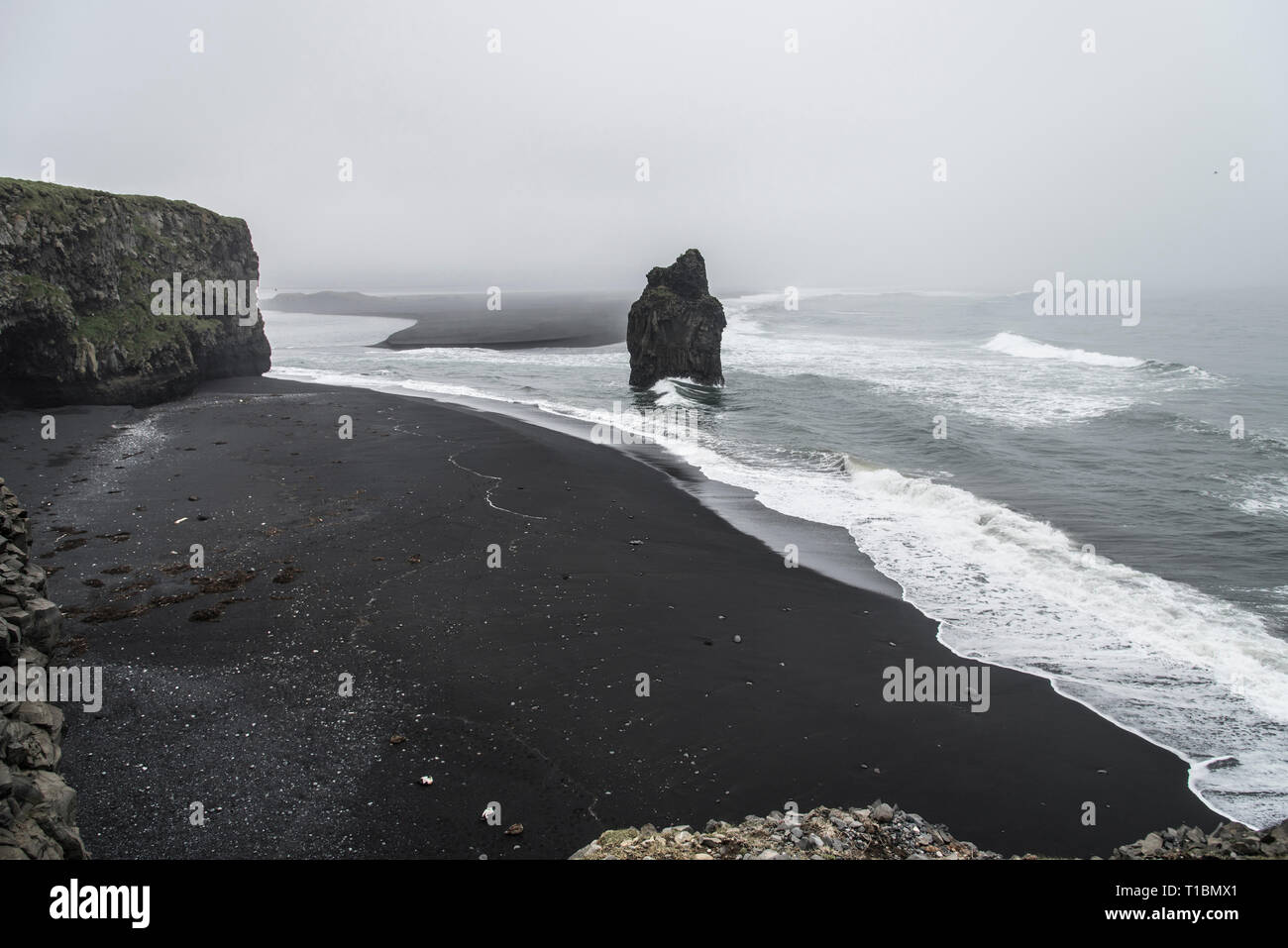 Kirkjufjara beach en Islande montrant des falaises et formations rocheuses sur un jour nuageux, brumeux Banque D'Images