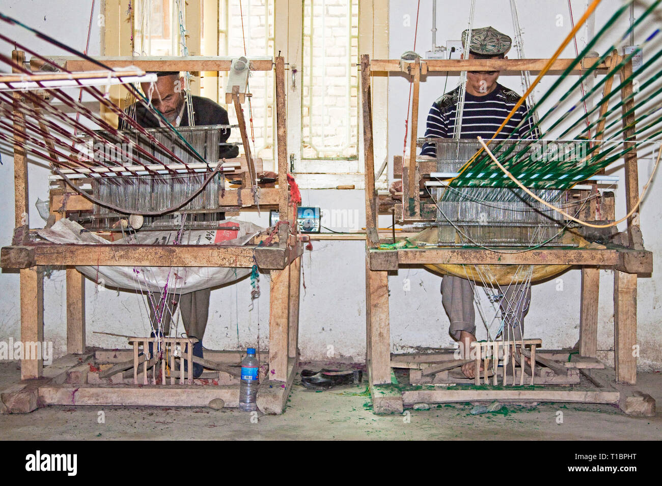 Tissage de silks multicolores (atlas, à Uyghur), un artisanat traditionnel de l'Uyghur. Atelier Atlas Silk, Hotan, région autonome du Xinjiang, Chine. Banque D'Images