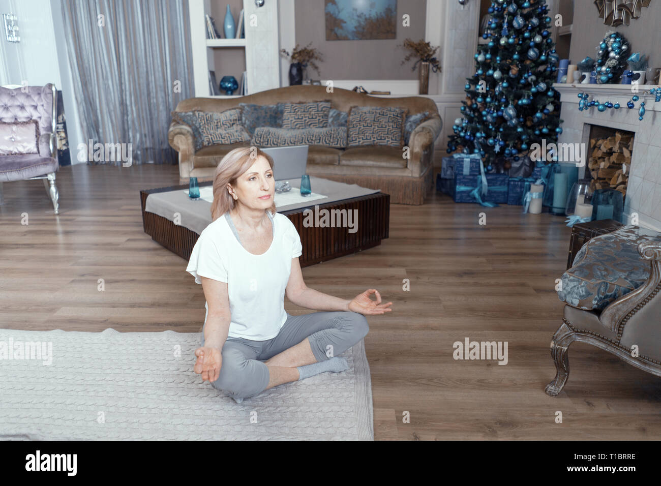 Une femme adulte médite après avoir fait du Yoga à la maison dans le salon. Banque D'Images