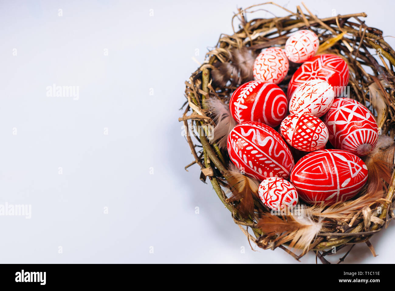 Pâques oeufs rouge avec motif blanc folk à l'intérieur de nids d'oiseaux sur fond blanc. Vue d'en haut. Les œufs traditionnels ukrainiens et krashanka pisanka Banque D'Images