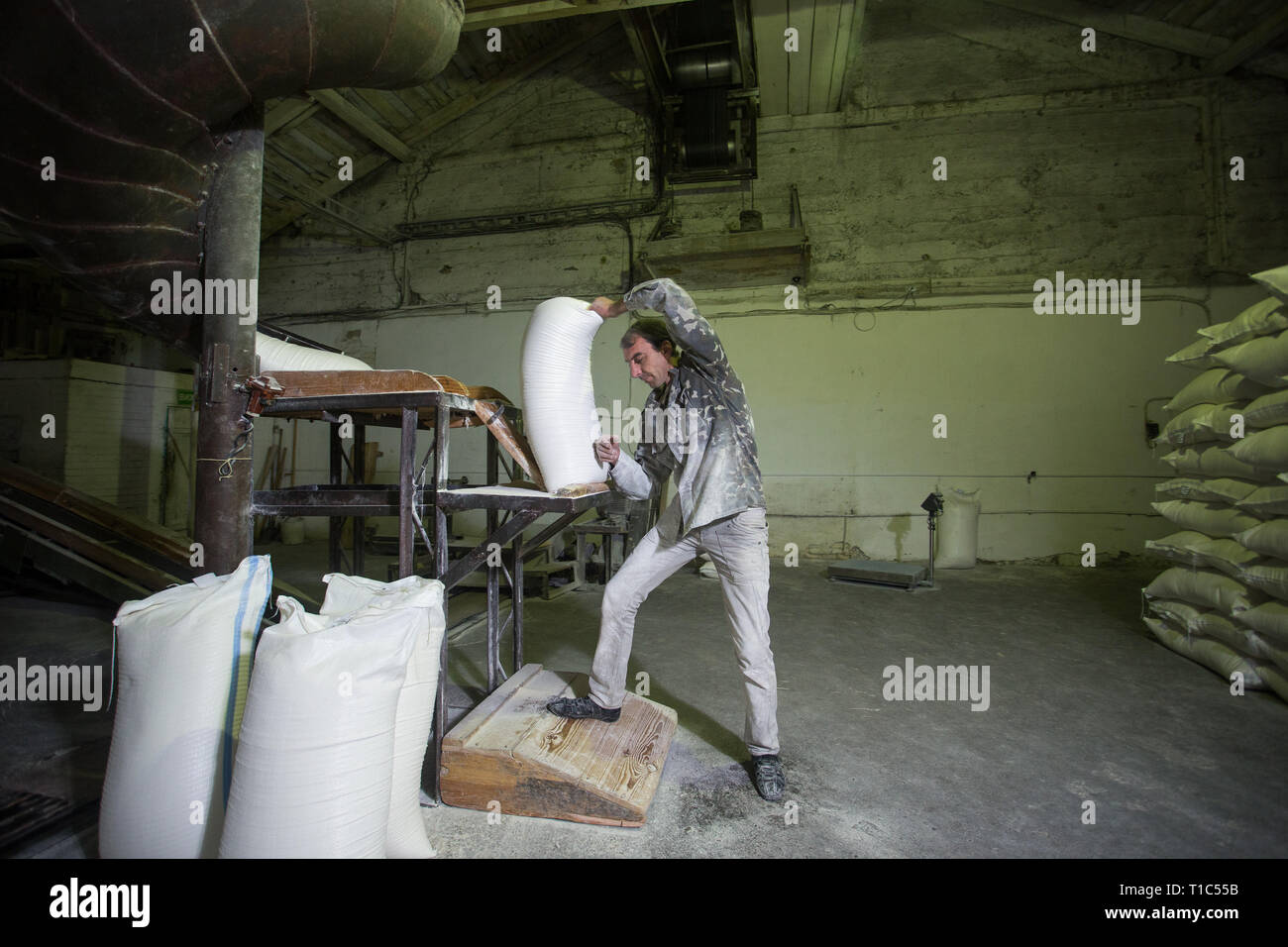 Le thème est une usine de travail. Un homme de race blanche porte des sacs de produits finis dans une ancienne usine. Le travail physique de la production dans l'après-So Banque D'Images