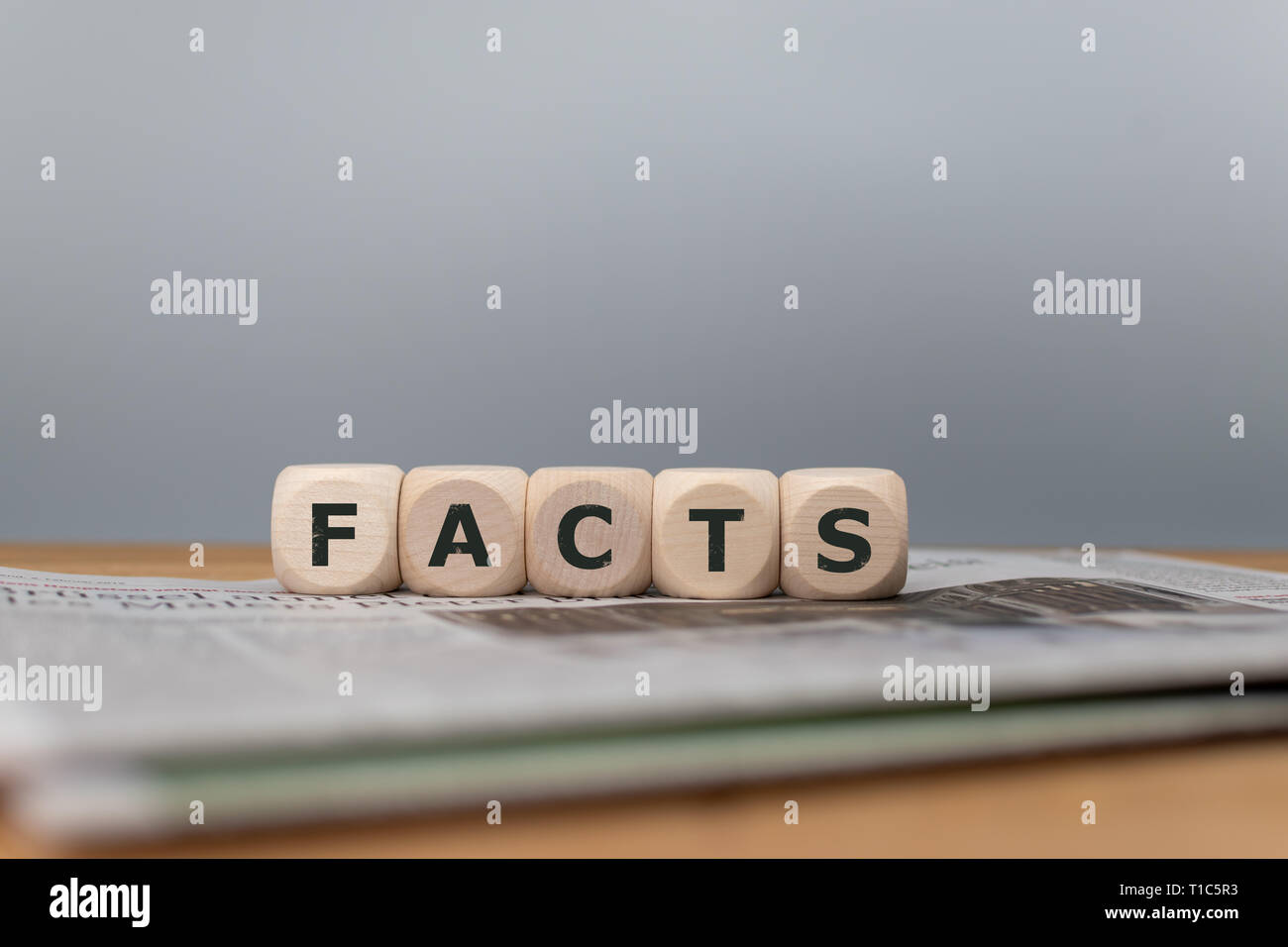 Dés placés sur un journal forment le mot 'faits'. Banque D'Images