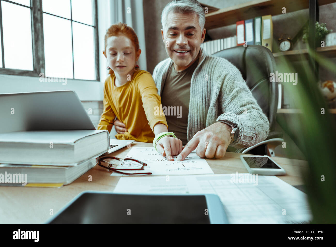 Belle homme positif d'aider sa fille à lire Banque D'Images
