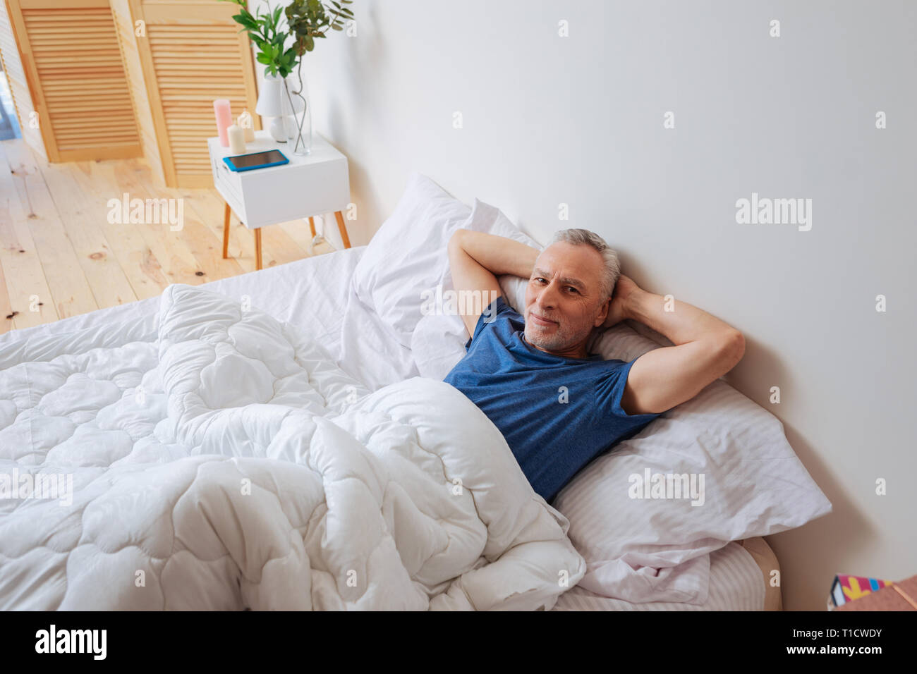 Homme aux cheveux gris barbu au frais dans son lit pendant le week-end. Banque D'Images