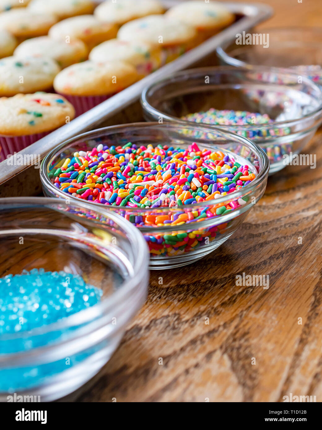 Bols de givre saupoudre alignés à côté d'un pan de mini cupcakes en préparation de frosting cupcakes. Banque D'Images