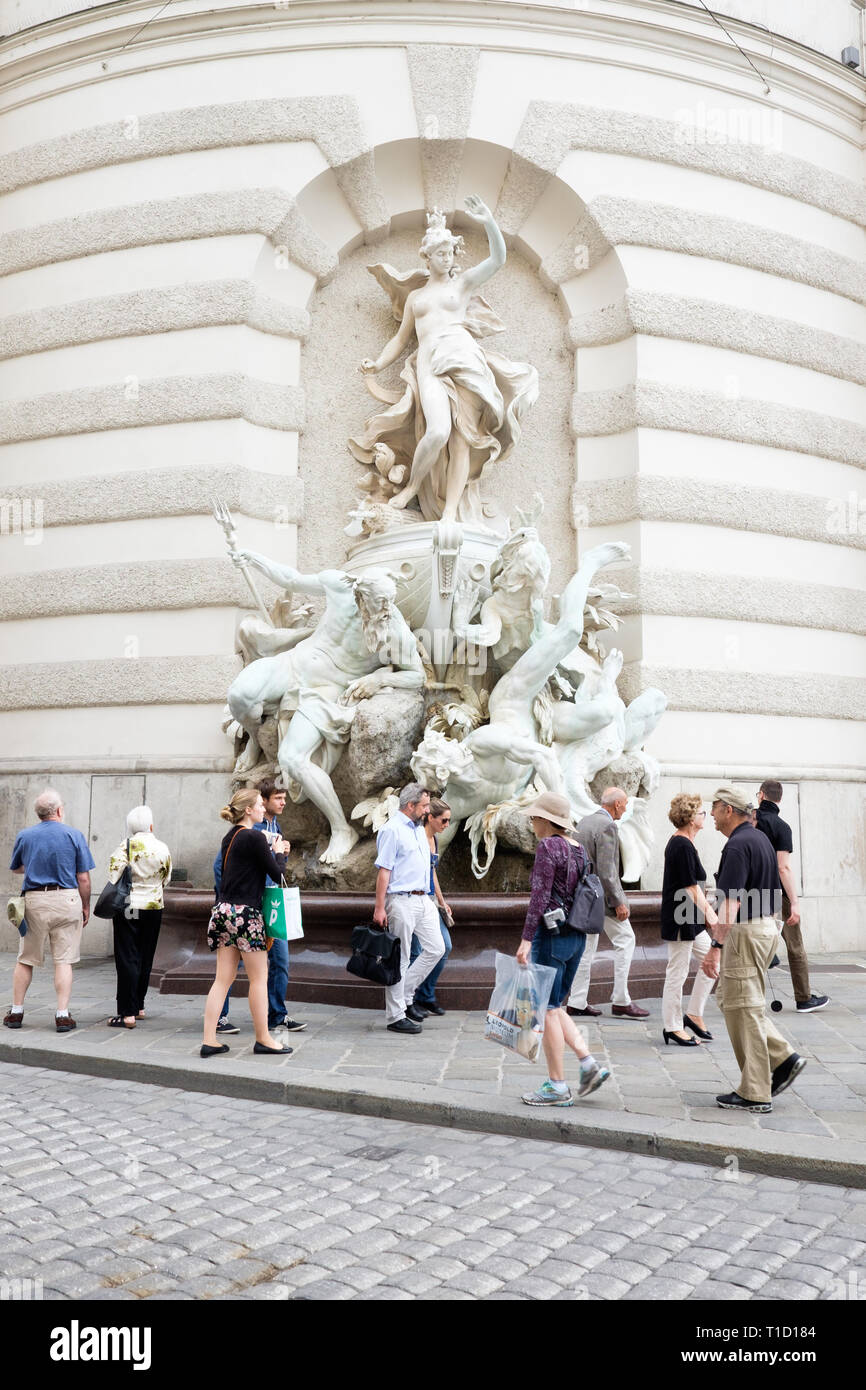 Promenade touristique passé la puissance en mer fontaine sculptée par Rudolf Weyr sur la façade de Saint Michael's Wing de la Hofburg à Vienne, Autriche. Banque D'Images