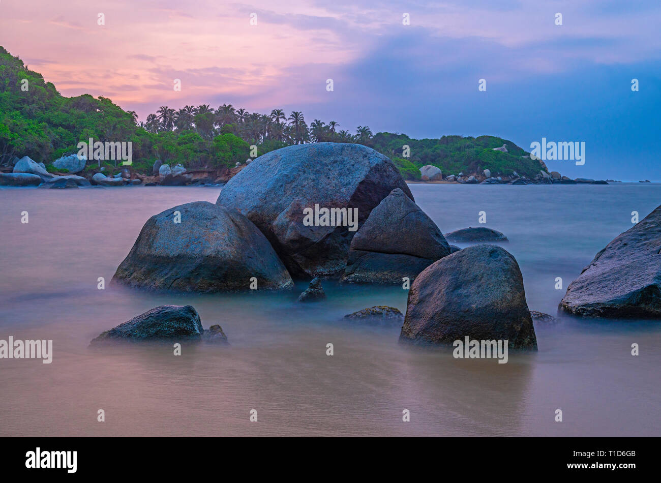 Des rochers volcaniques et la mer des Caraïbes le long de la plage de parc national naturel de Tayrona avec la forêt tropicale à l'arrière-plan, Santa Marta, Colombie. Banque D'Images