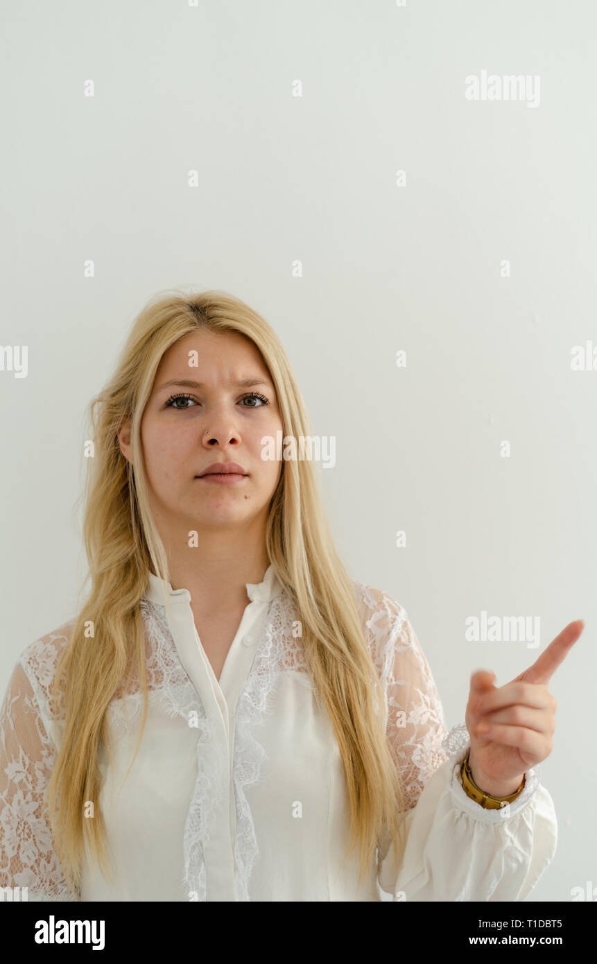 Jeune femme malheureuse émotionnelle glamour habillé de dentelle shirt froncer et faisant la moue, ayant perturbé grognon regardez, élever l'index négatif.Les droits de l'aec Banque D'Images