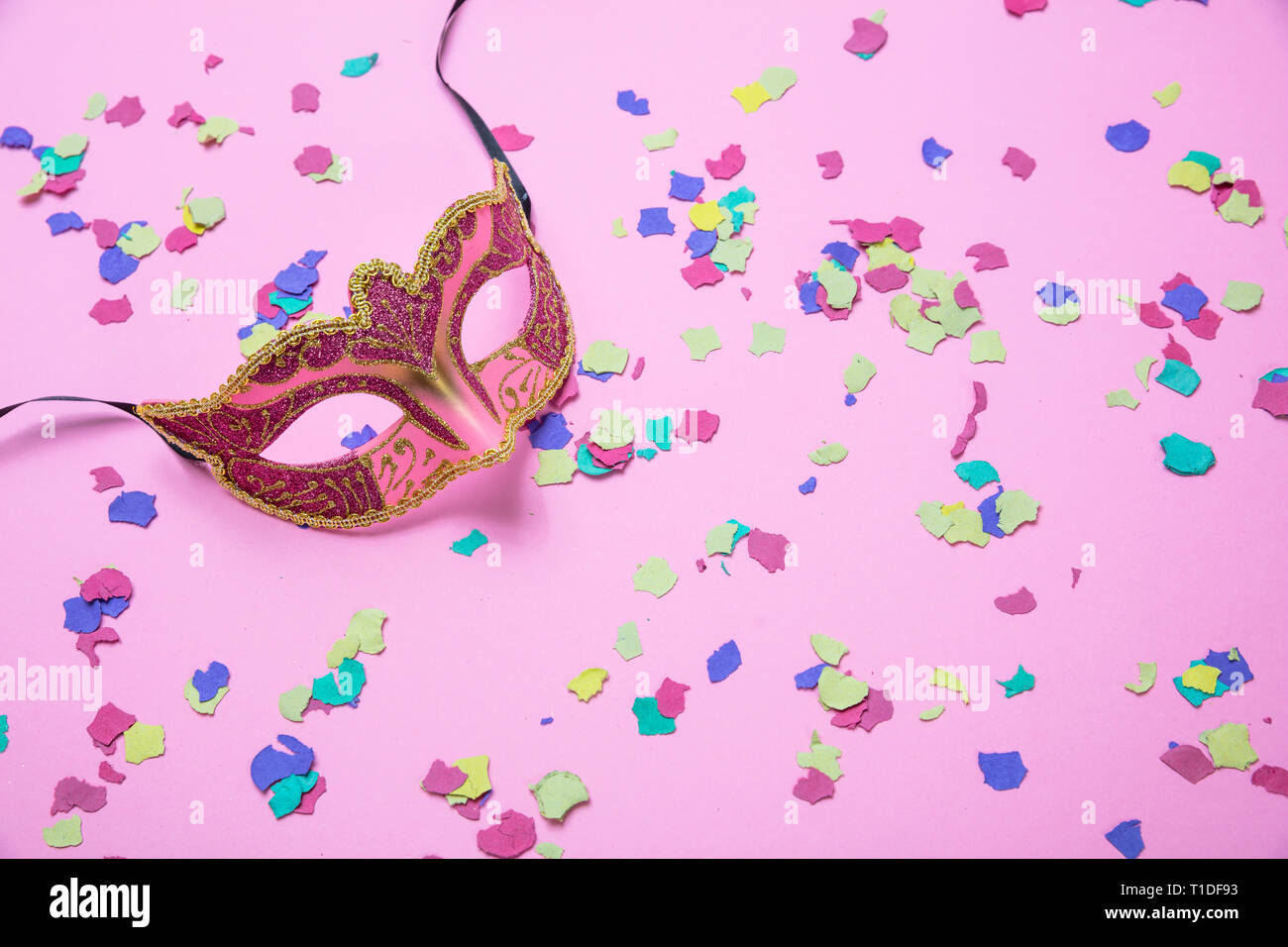 Carnaval, fête d'anniversaire. Femme masque de Venise et de confettis colorés sur fond rose Banque D'Images