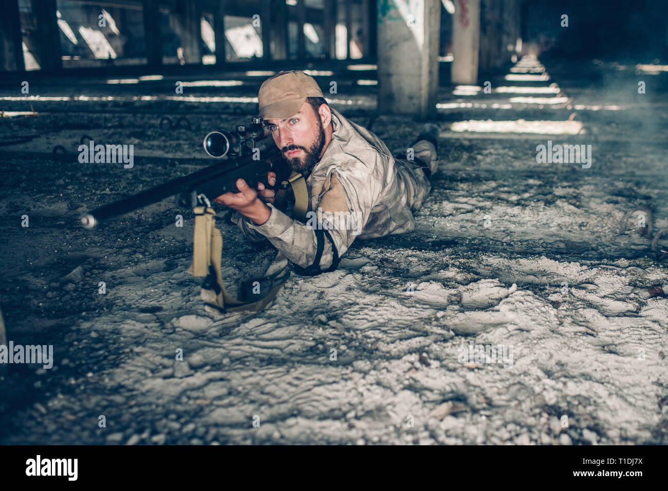 Homme sérieux et professionnel est allongé sur le sol et regardant à travers la lentille. Il est en train de prendre fin. Guy porte des vêtements militaires. Il est en attente. Banque D'Images