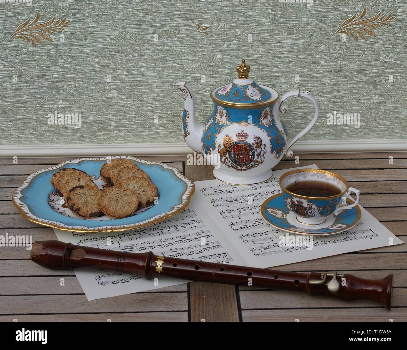 Verre d'anglais avec soucoupe, théière et un gâteau avec les cookies, céramique fine porcelaine, et une flûte de bloc sur une feuille de musique Banque D'Images