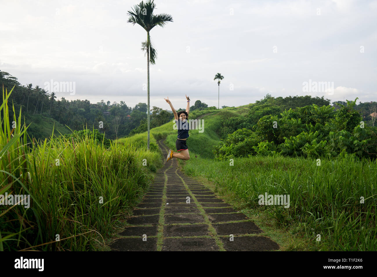 Happy girl saute au milieu d'une piste de jogging au Ubud Bali Banque D'Images