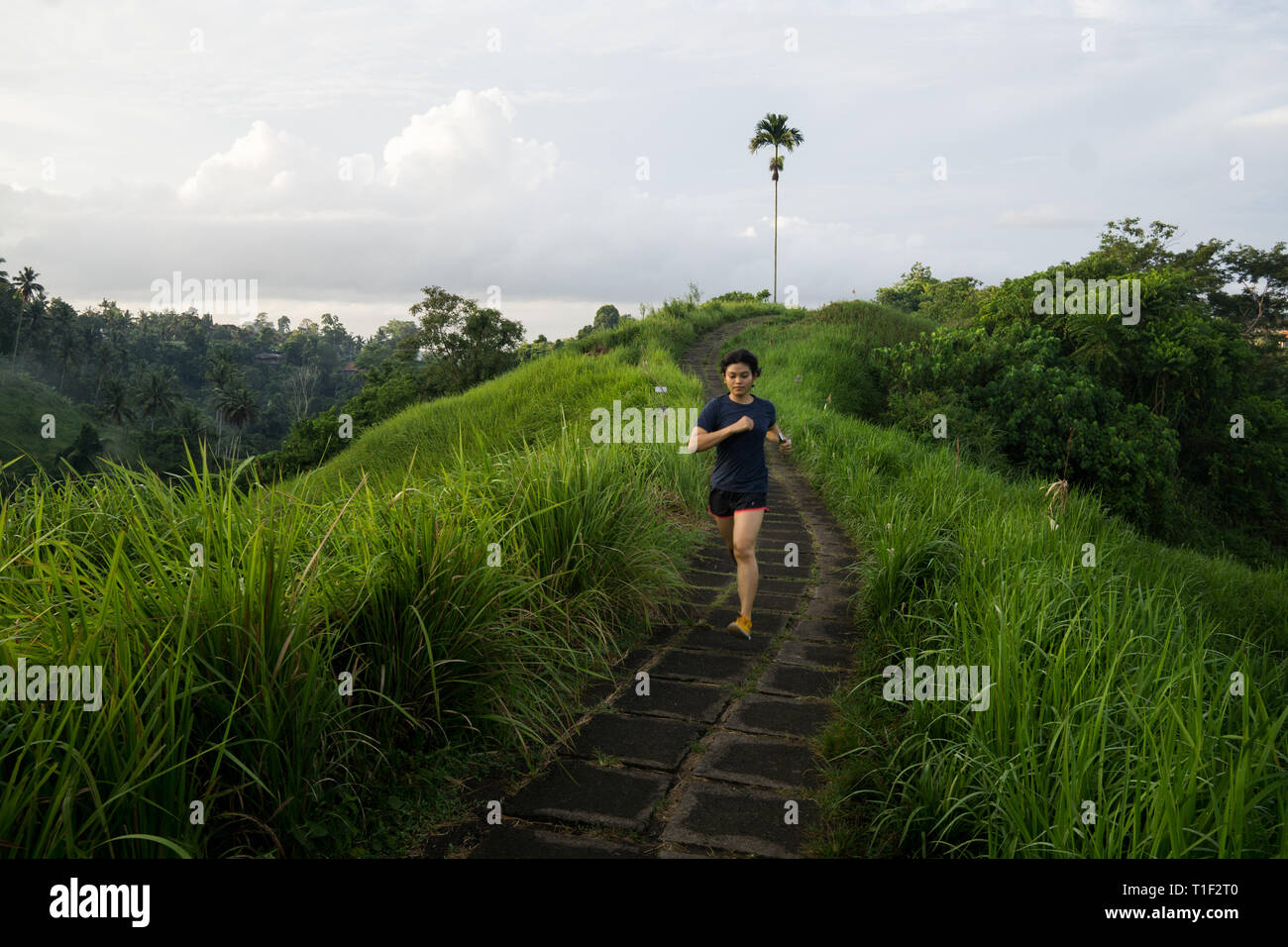 Happy girl saute au milieu d'une piste de jogging au Ubud Bali Banque D'Images