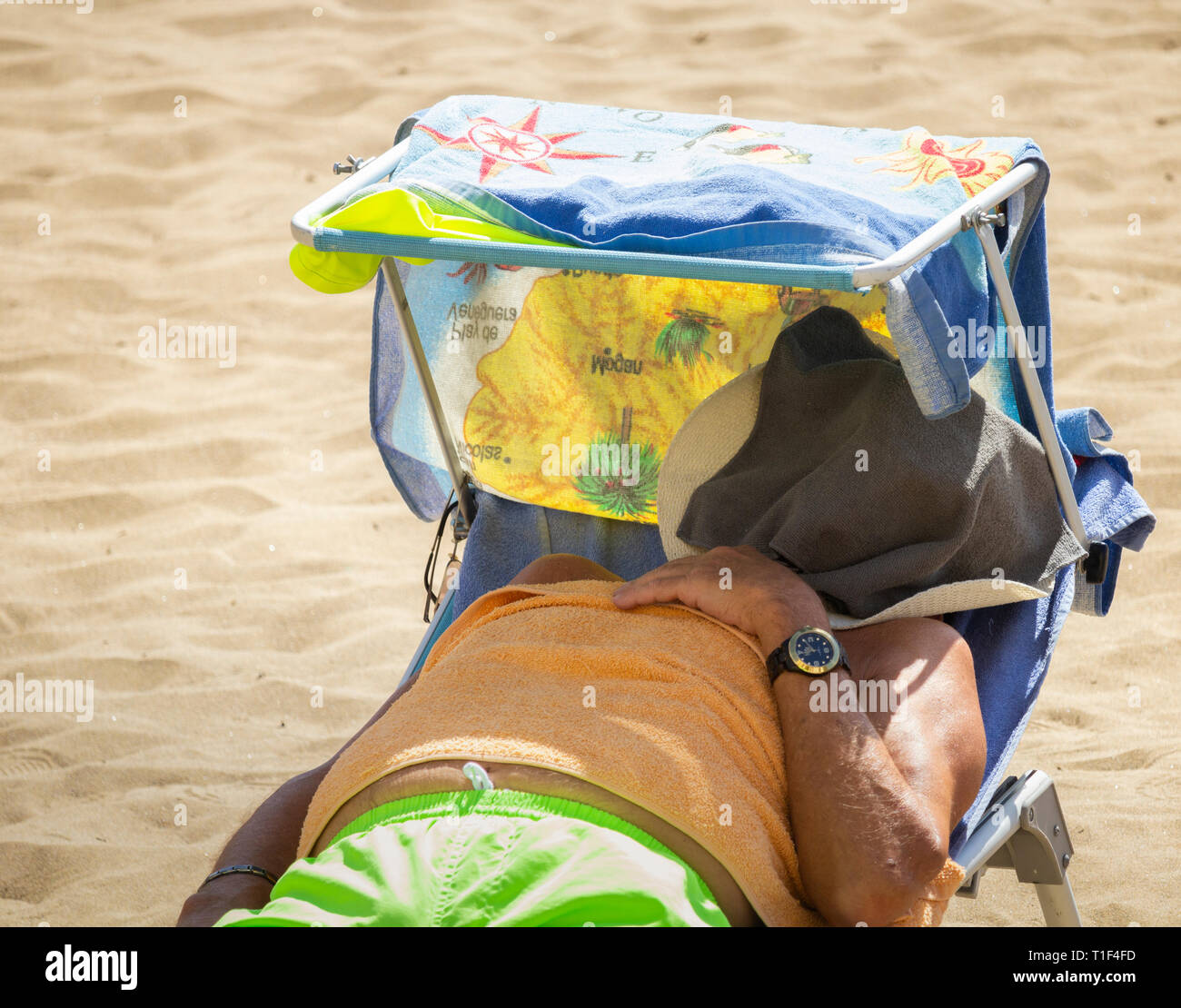 Homme prenant un bain de soleil sur une chaise longue de plage pendant la vague de chaleur. Banque D'Images