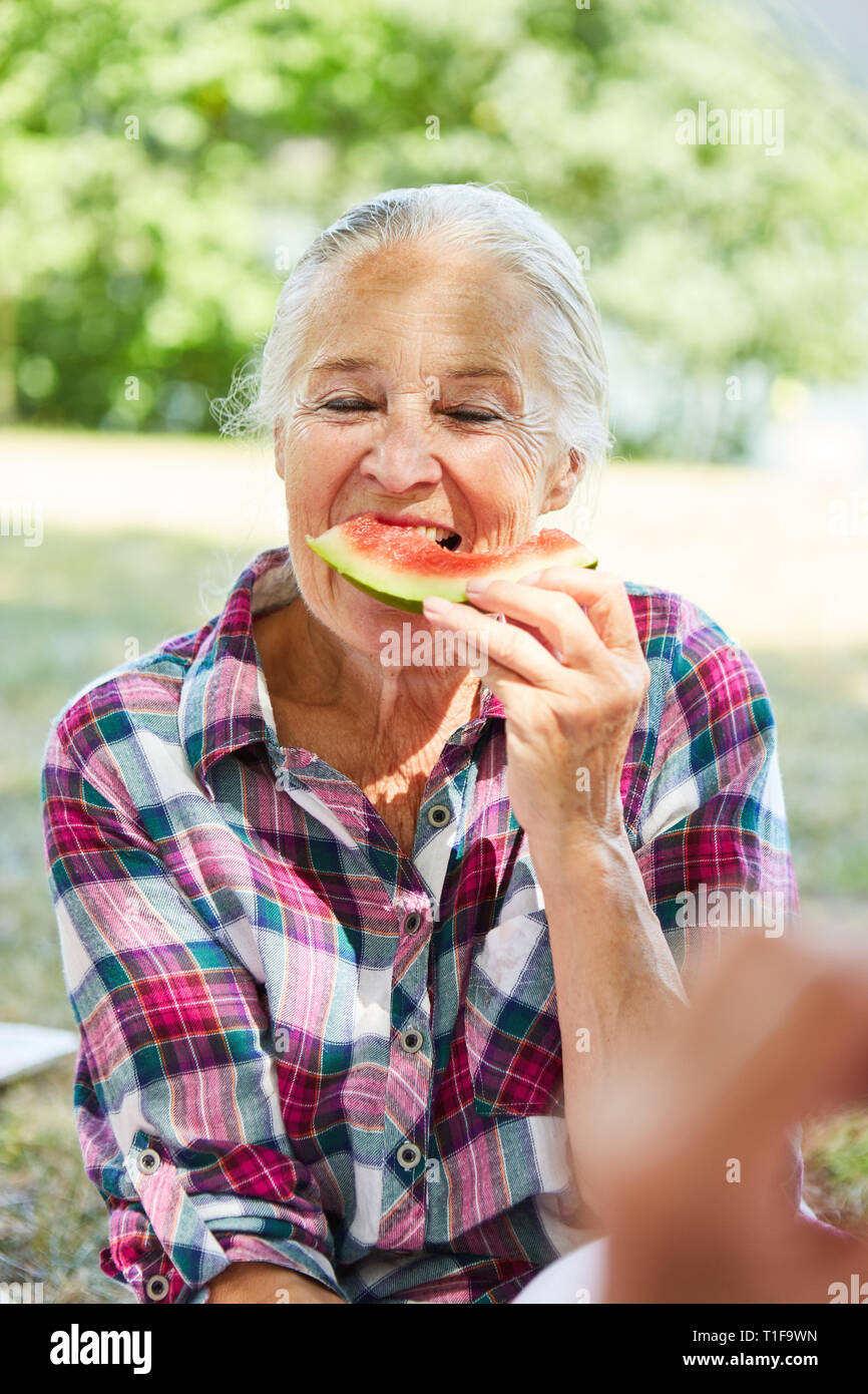 Hungry Man est en train de manger une pastèque dans le parc dans le cadre d'un voyage à l'été Banque D'Images