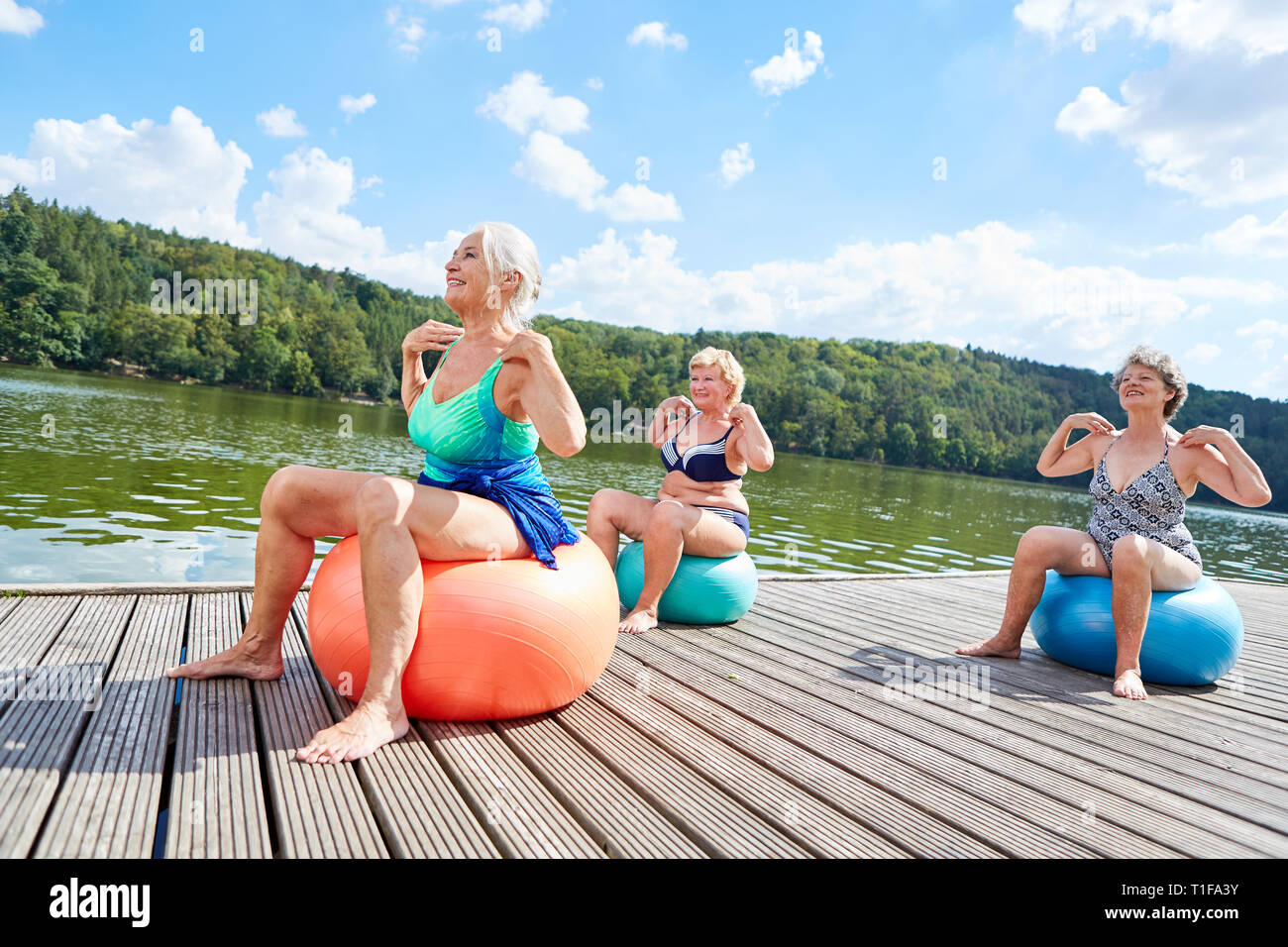 Trois femmes âgées avec ballon de gymnastique au cours de la formation retour en rehab à la rive du lac Banque D'Images