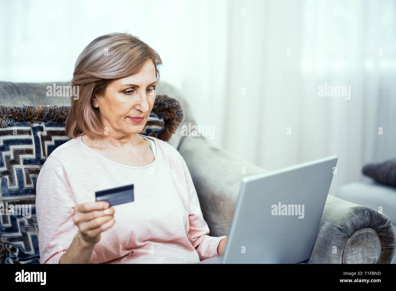 Une femme âgée avec une carte de crédit dans sa main paie pour un achat en ligne. Banque D'Images Une femme âgée avec une carte de crédit dans sa main paie pour un achat en ligne. Banque D'Images
