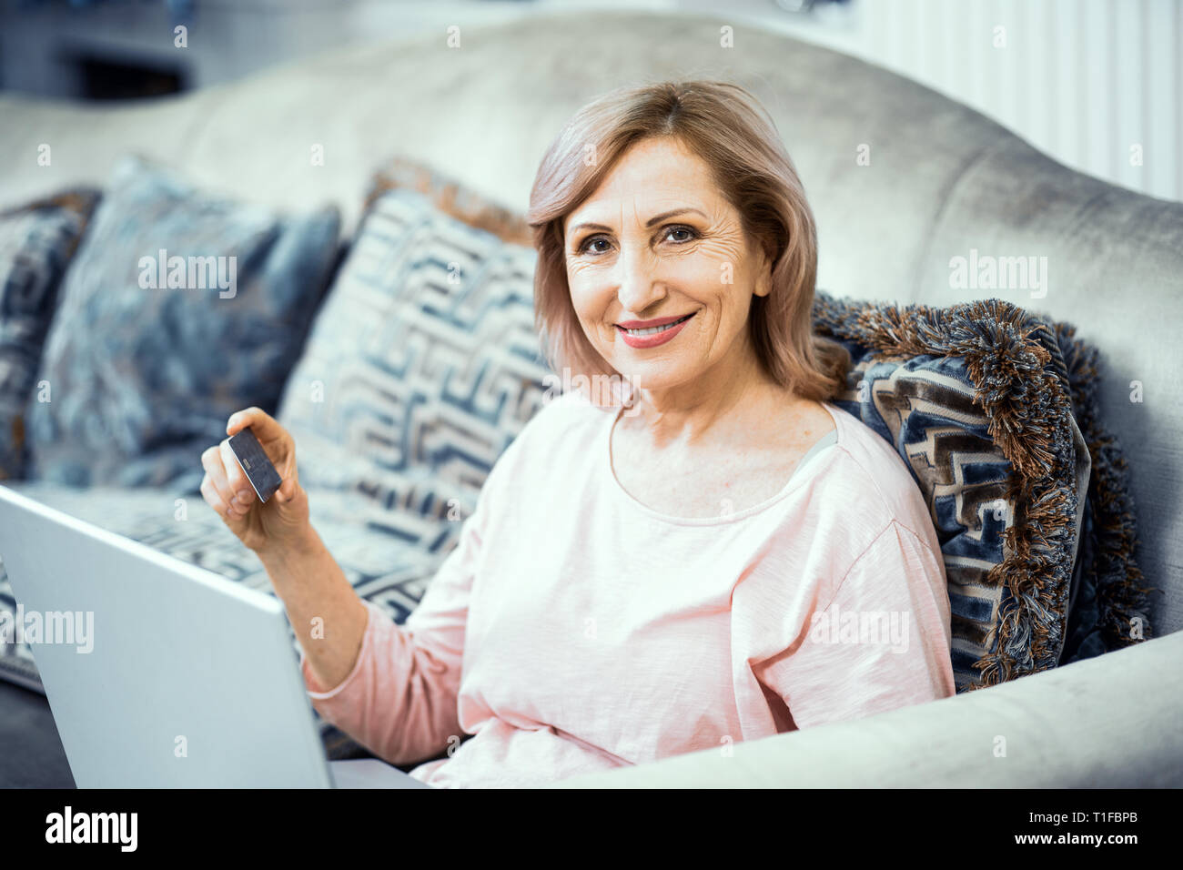 Une femme âgée avec une carte de crédit dans sa main paie pour un achat en ligne. Banque D'Images Une femme âgée avec une carte de crédit dans sa main paie pour un achat en ligne. Banque D'Images