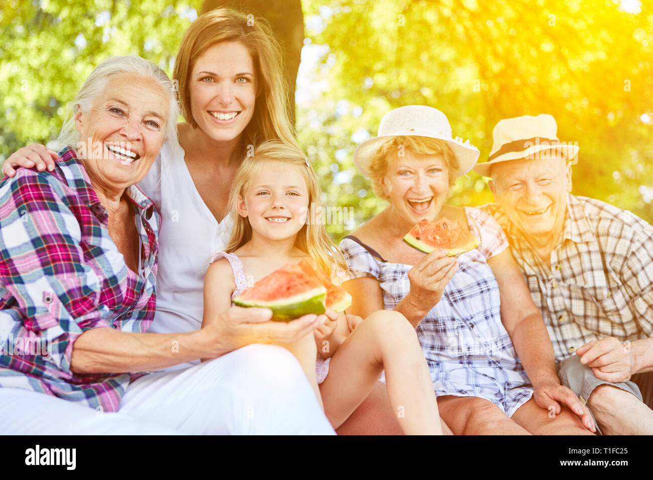 La famille élargie dans le melon rire manger dans le jardin d'été Banque D'Images