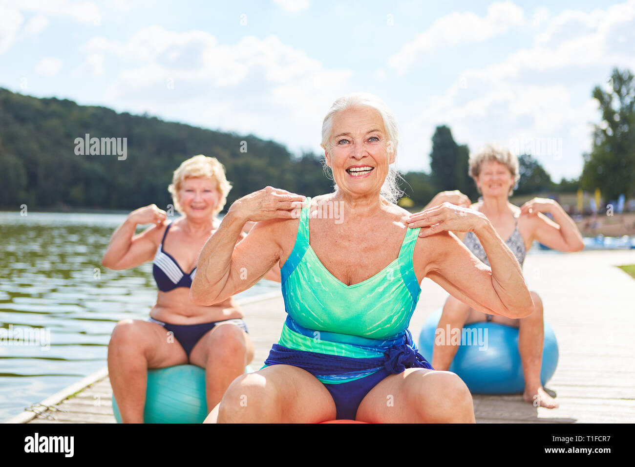 Senior Vital avec ballon de gymnastique fait un entraînement avec des amis au bord du lac Banque D'Images