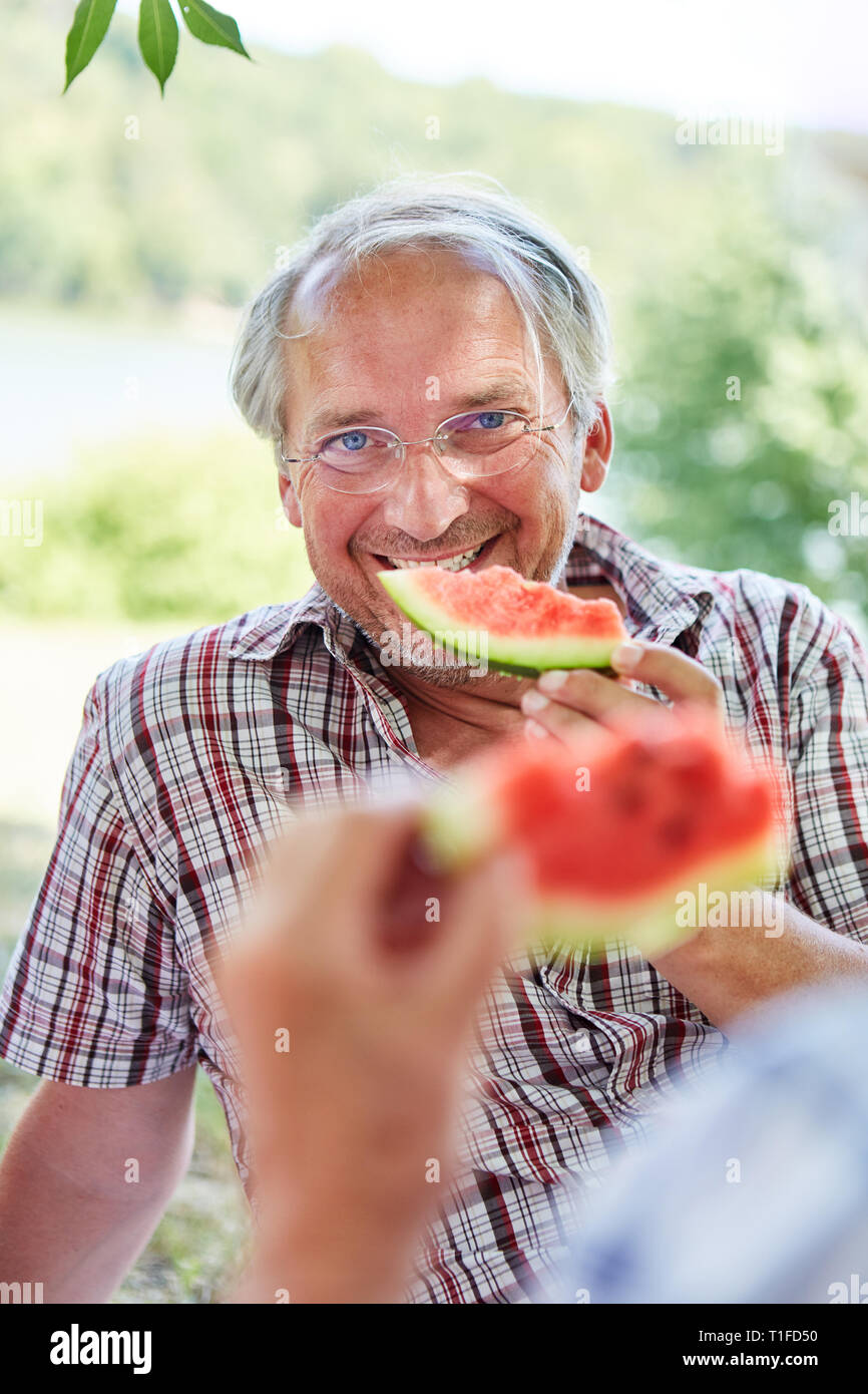 Man sur une sortie d'été dans la nature manger melon Banque D'Images