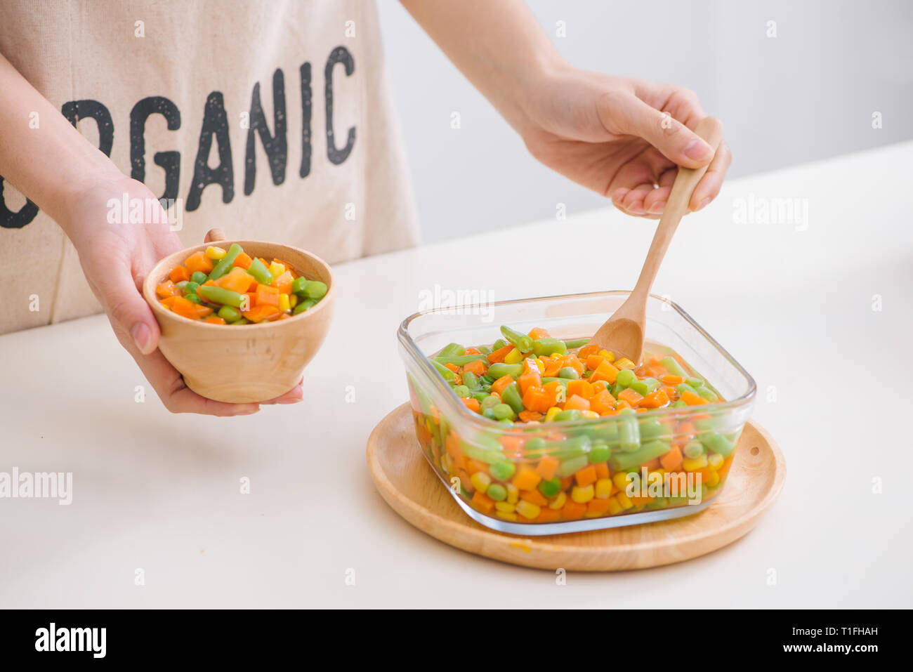 Louche de jeunes légumes fraîchement récoltés à la vapeur y compris les carottes, en Coupe ondulée, de pois et de pommes de terre pour un accompagnement sain pour le dîner Banque D'Images