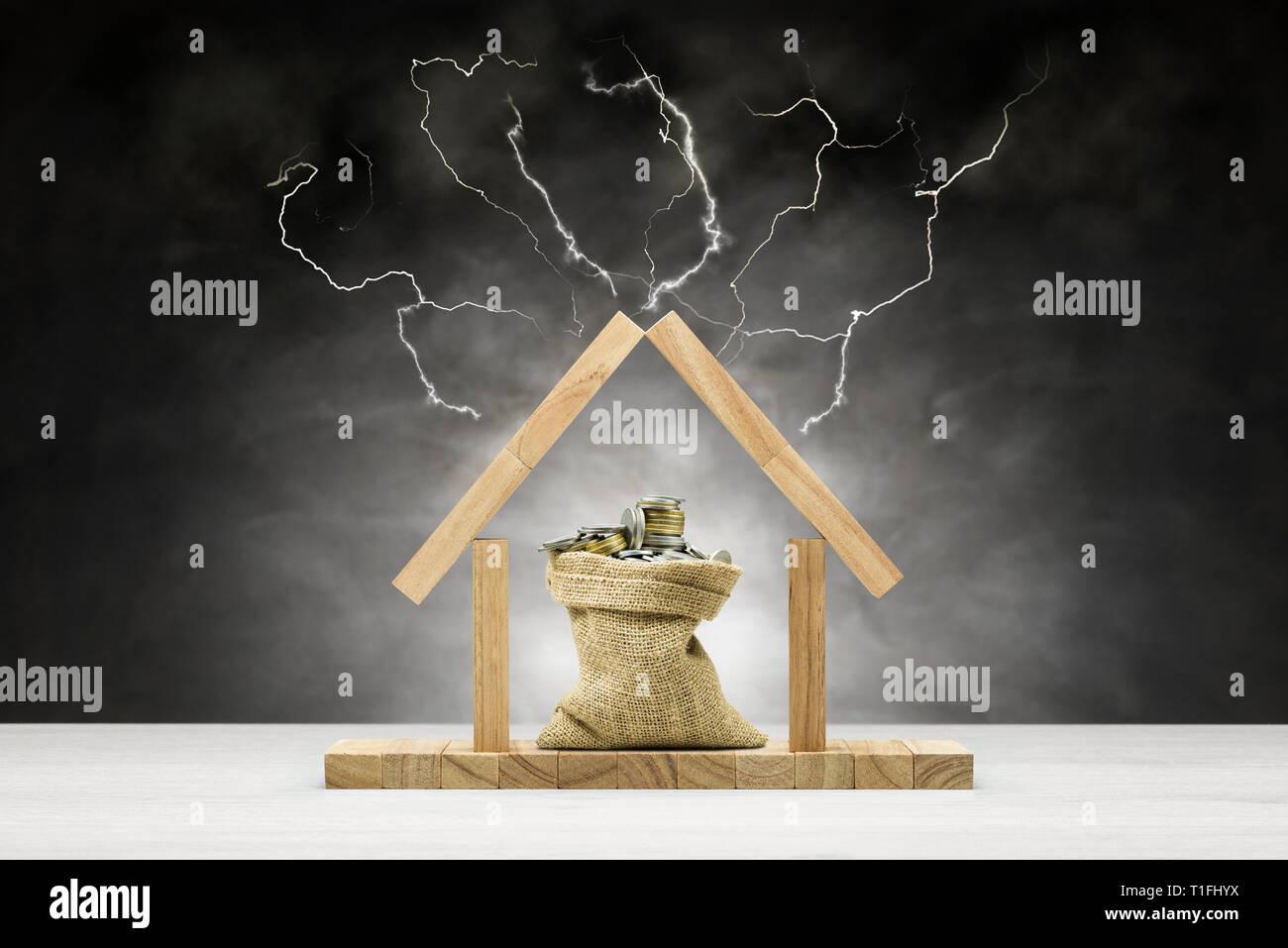 Concept de protection de l'environnement, maison en bois sur fond gris avec sac plein de pièces sous le toit et la foudre Banque D'Images