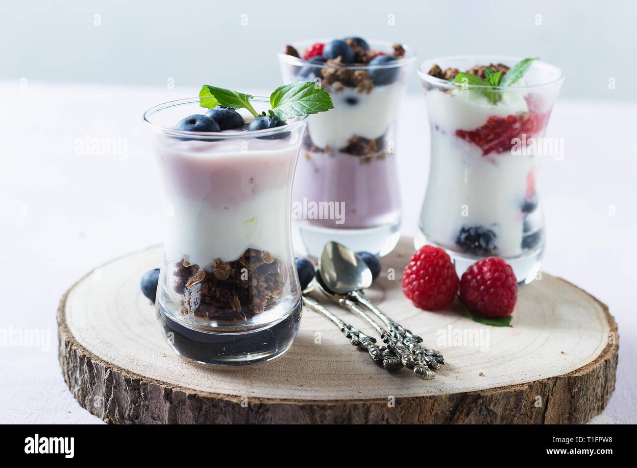 Lunettes avec fruit les parfaits composé de yaourts, céréales, bleuets et framboises avec cuillères décorées Banque D'Images