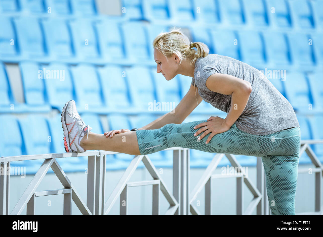 Woman runner étirements avant l'exécution de la formation au stadium Banque D'Images