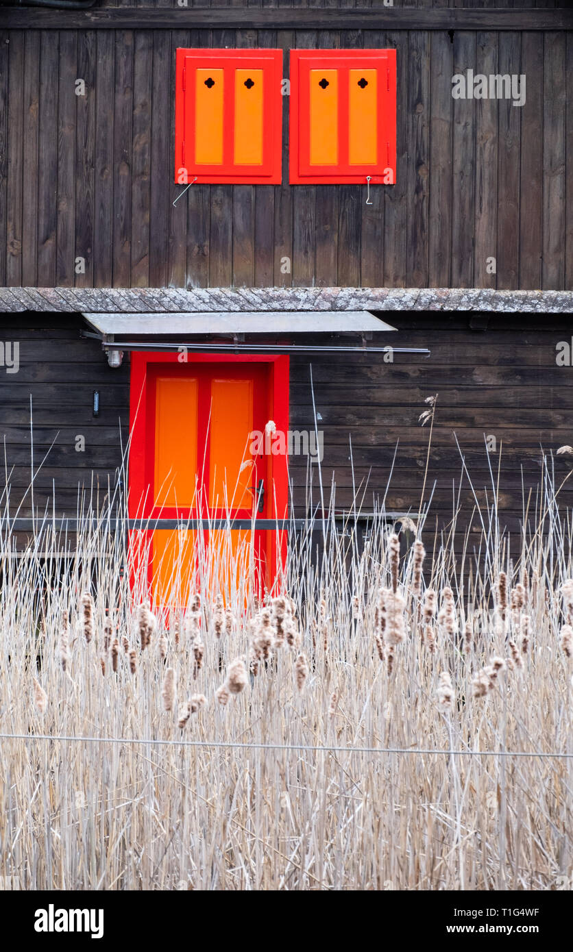 Vieille cabane en bois brun rouge et orange avec windows dans le lac Wörthersee de roseaux devant Banque D'Images