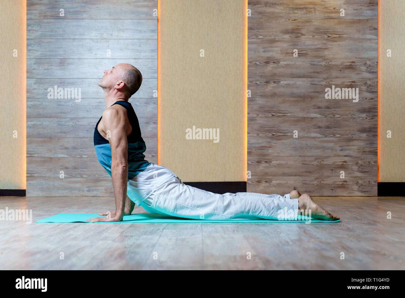 L'homme pratique le yoga sur le tapis bleu . Banque D'Images