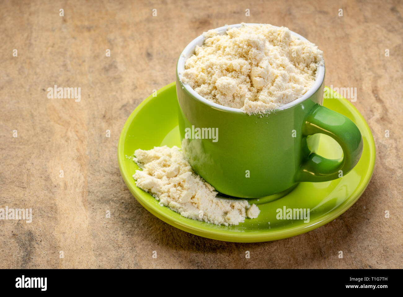 La poudre de protéine de petit lait dans une tasse de café contre l'écorce texturée paper Banque D'Images